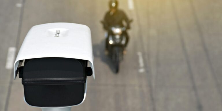 Image of a motorcycle driving underneath a security camera