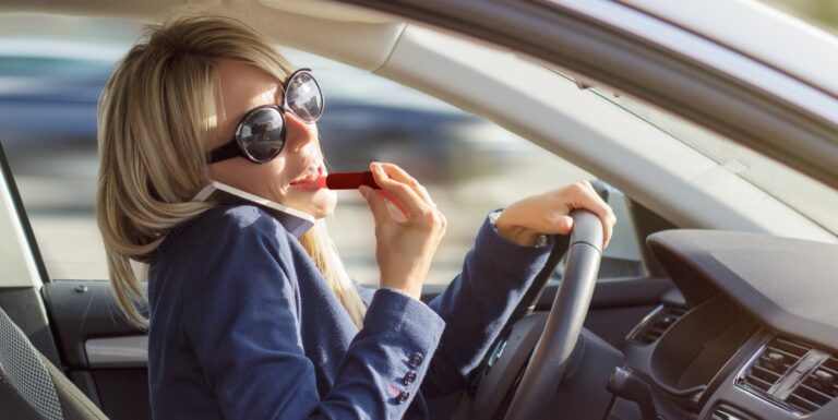 Image of a woman talking on the phone and applying lipstick while driviing