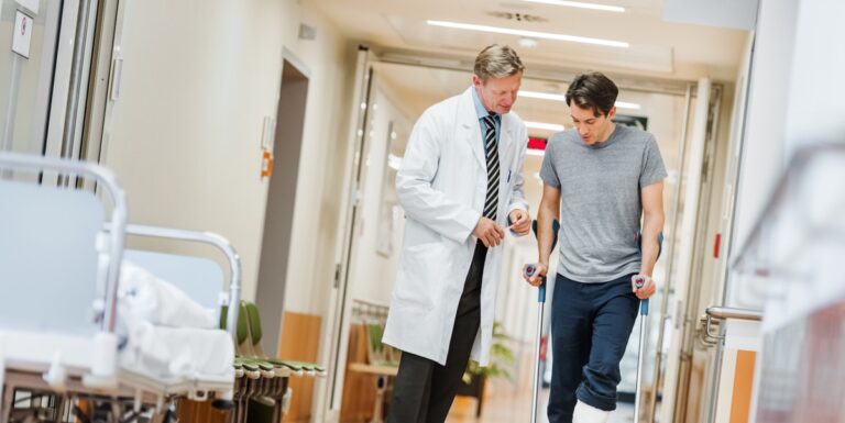 Image of a doctor helping a man use crutches