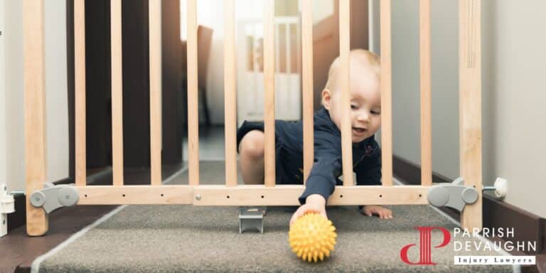 Image of a baby sitting behind a baby gate placed in front of a staircase