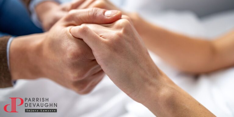 Image of a close-up of a pair of people clutching hands over a hospital bed
