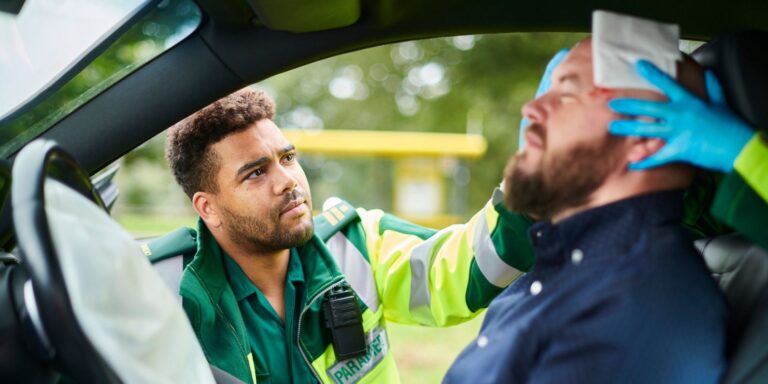 Image of a paramedic checking out a main in a car after a crash